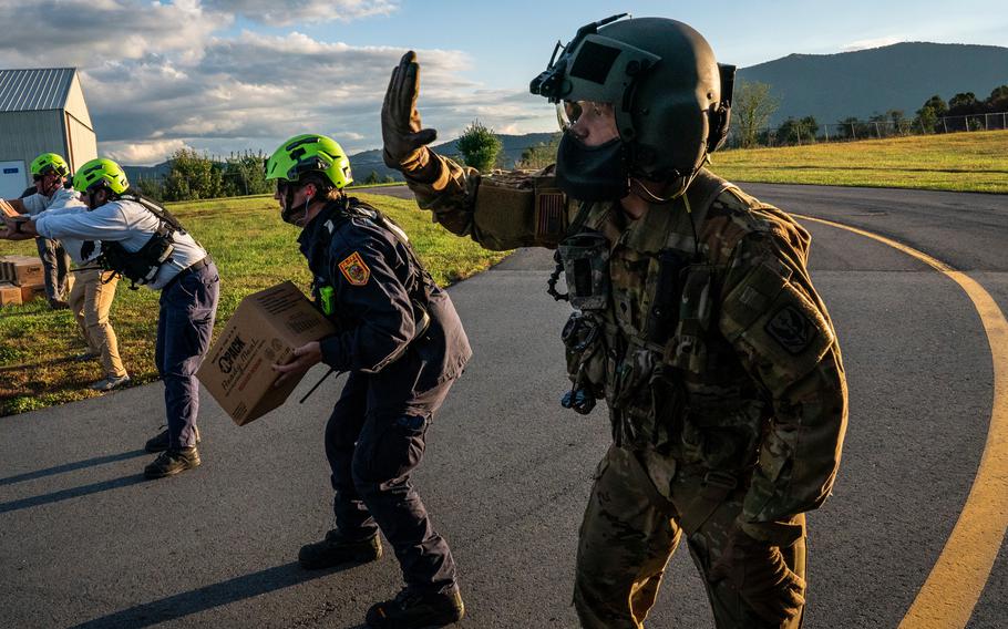 A National Guard member holds a hand up while standing next to members of FEMA and other aid workers.