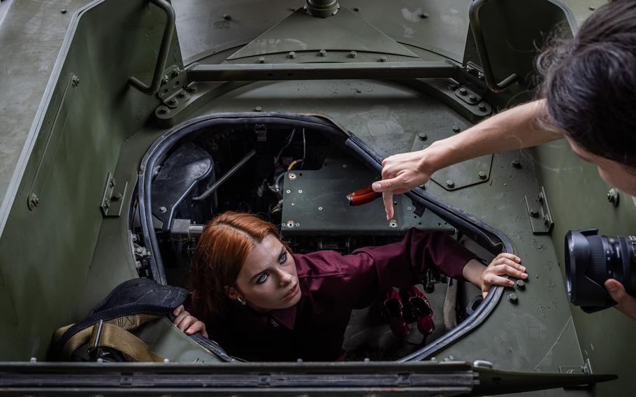 Model Arina sits in a Humvee and gets directions from a photographer.