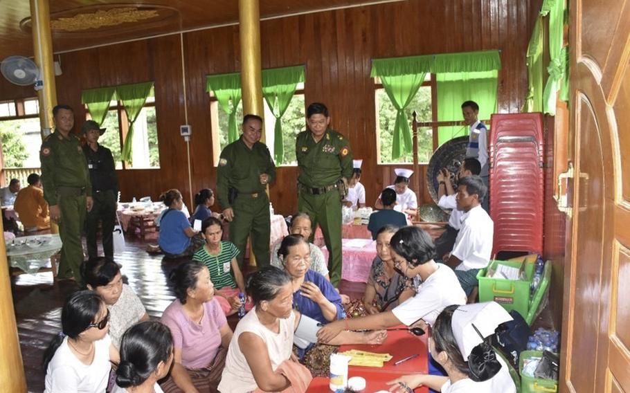 Military officials inspect while flood victims receive medical treatment