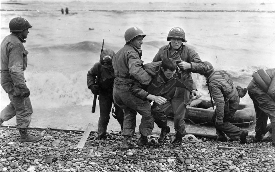 Medics from the U.S. 5th and 6th Engineer Special Brigade (ESB) help wounded soldiers on Omaha beach, Fox Green and Easy Red sectors. Survivors of sunken landing craft who reached the beach by using a life raft are recovered by other troops.