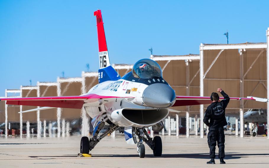 An airman stands on the tarmac in front of an F-16.