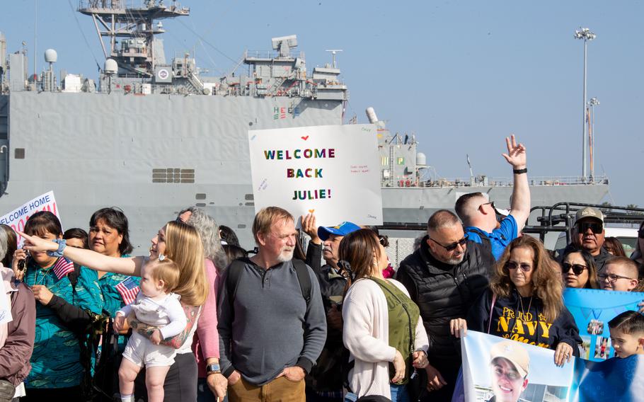 Family and loved ones hold signs during a homecoming ceremony for the USS Stockdale