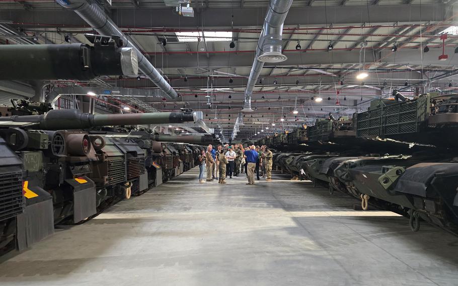 Congressional and U.S. Embassy staff members tour a storage warehouses filled with military vehicles in Poland.