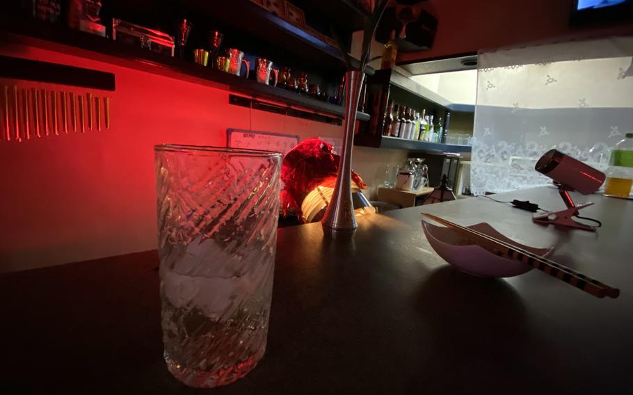 A glass sits on a table at a bar in Japan.