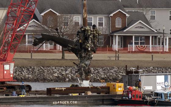 Salvage crews pull up a part of a Black Hawk helicopter from a river.