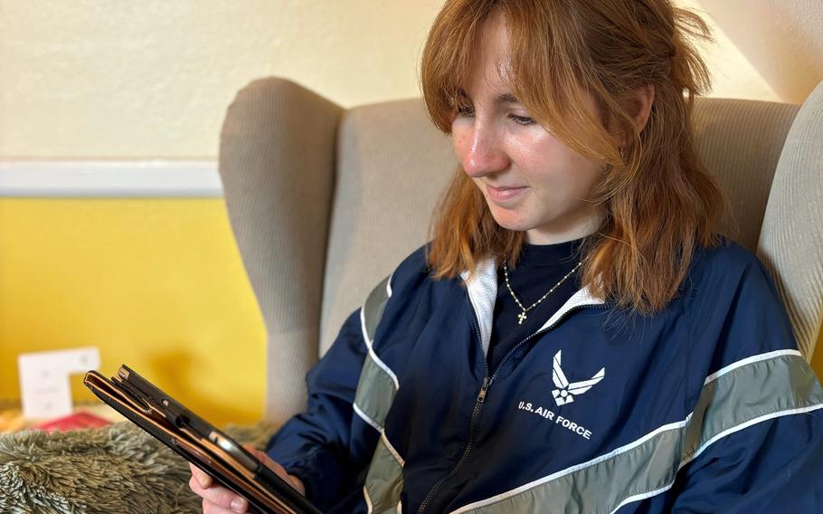 A woman in an Air Force jacket watches streamed content on a tablet.