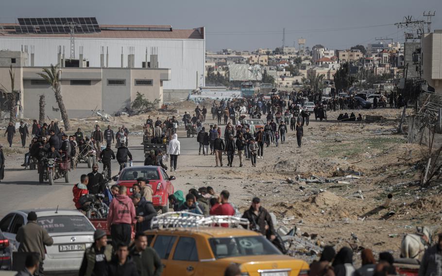 A long line of Palestinians walk along a road headed home.