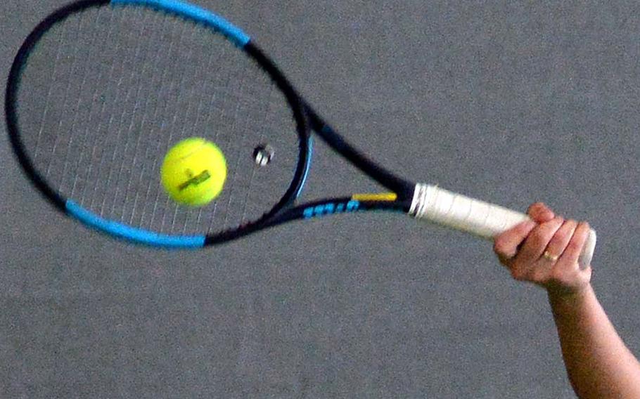 A tennis player hits the ball with her racket.