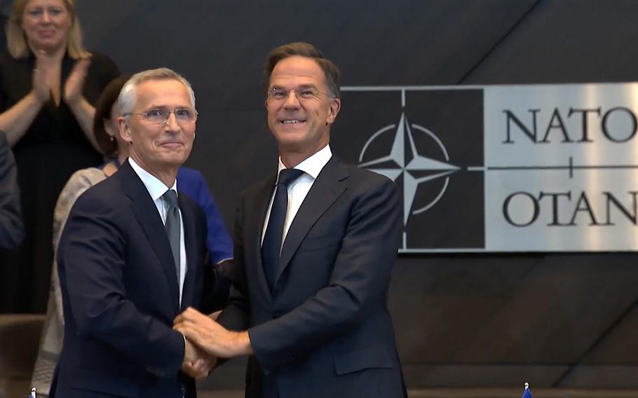 New NATO Secretary-General Mark Rutte shakes hands with his predecessor Jens Stoltenberg at NATO headquarters in Brussels.