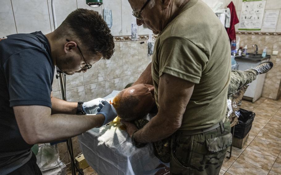 A medical team carefully removes a fragment of shrapnel from the back of a soldier’s head after he was wounded in a Russian cluster bomb attack near Bakhmut, Ukraine.