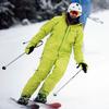 A man in a green snow suit and white helmet skis down a snowy slope.