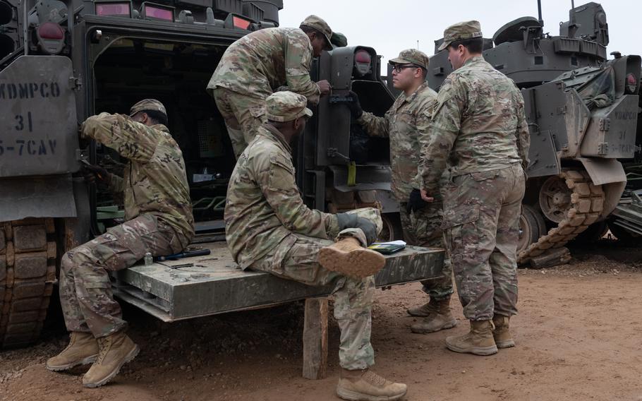 A group of soldiers works on a vehicle.