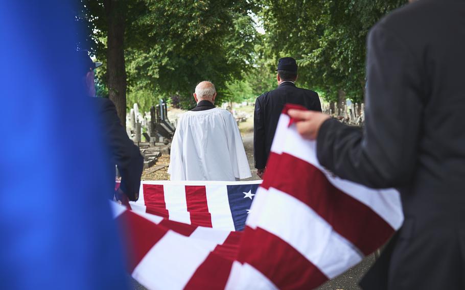 A chaplain, left, and Mathew O’Neill, the Sons of Union Veterans of the Civil War camp commander, lead the carrying of the flag to drape over the grave of Civil War veteran Pvt. James Schobel White at the East London Cemetery, England, Aug. 10, 2024. 