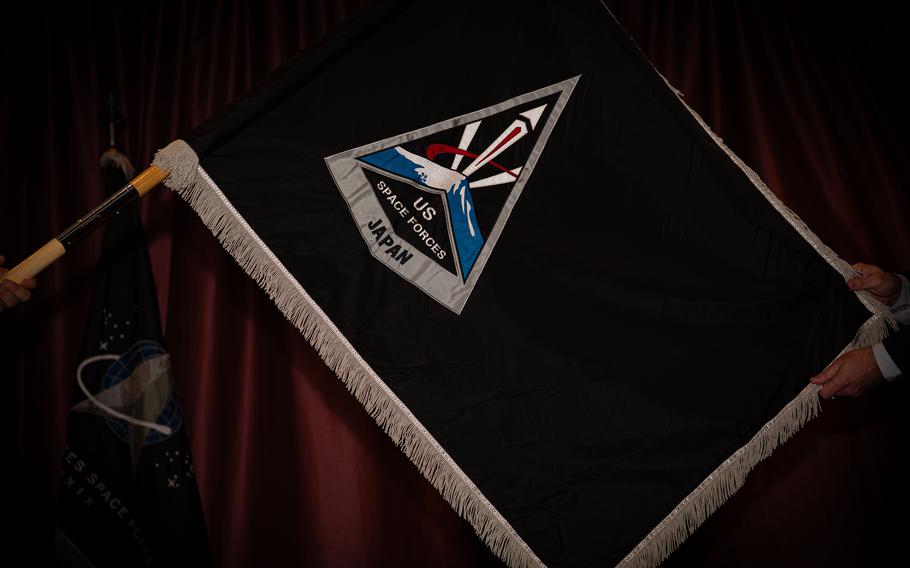 The flag for U.S. Space Forces Japan is seen against a velvet curtain.