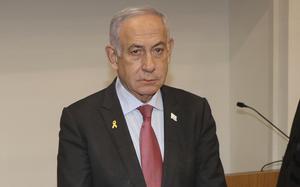 Israeli Prime Minister Benjamin Netanyahu, wearing a dark suit, stands in front of a microphone in a courtroom.