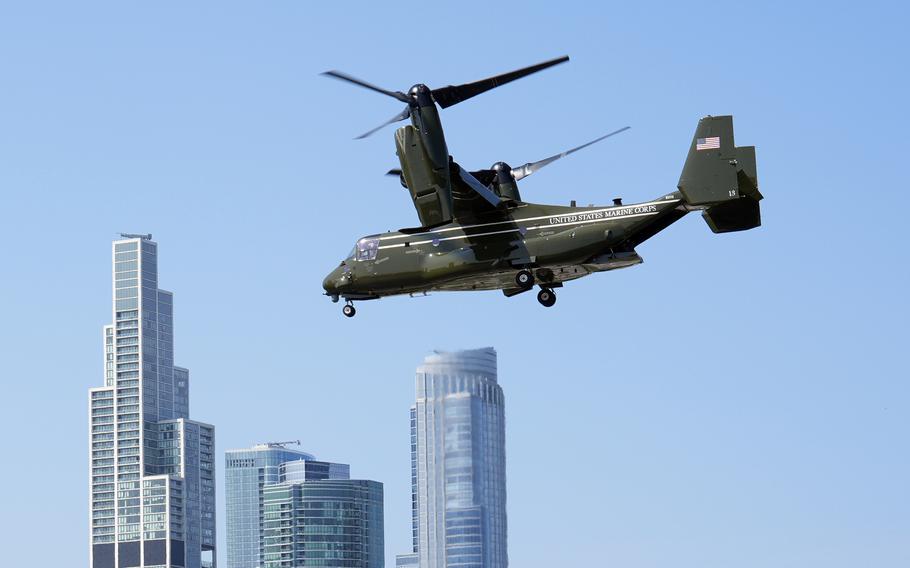 Marine Two, an Osprey, flies with Chicago skyscrapers and a blue sky in the background.