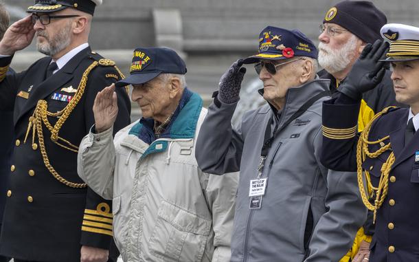 Battle of the Bulge veterans Frank Cohn, left, and Harry Miller, salute the presentation of the colors during the battleÕs 80th Anniversary wreath laying at the World War II MemorialÕs Circle of Remembrance, Dec. 16, 2024 in Washington. (Eric Kayne/Stars and Stripes)