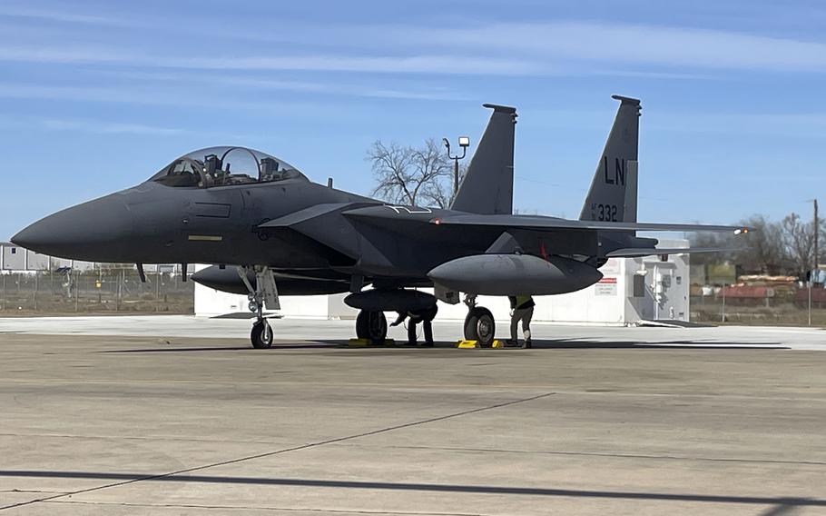 Two crew members work underneath an F-15E.