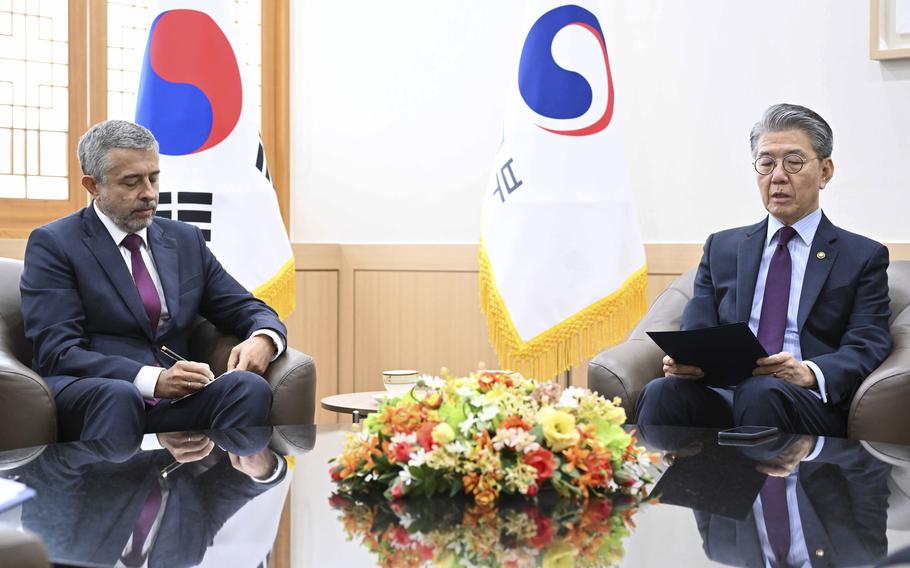 The Russian ambassador and South Korea’s vice foreign minister, both wearing suits, sit next to each other.