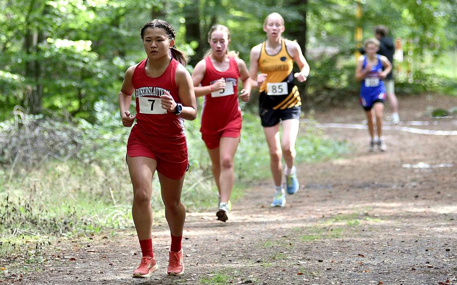 Kaiserslautern’s Uno Tate runs through the woods as teammate Bailey Wesseler and Stuttgart’s Klaryssa Lemery trail during a cross country meet on Sept. 14, 2024, at Ramstein High School on Ramstein Air Base, Germany.