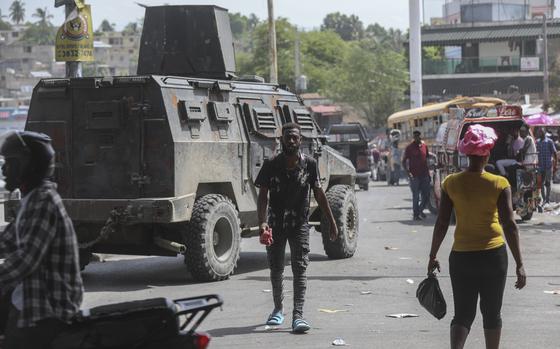 People walk past an armored police vehicle patrolling the streets in Port-au-Prince, Haiti, Monday, July 15, 2024. 