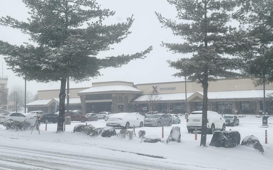 Cars covered in snow are shown parked in a shopping center.