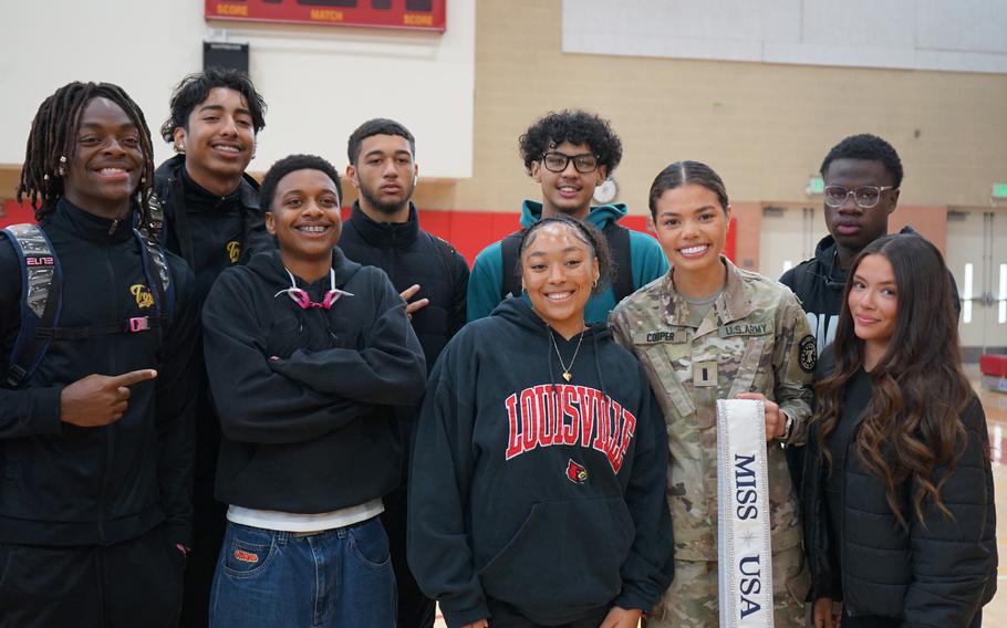 A soldier poses for a photo with a group of students