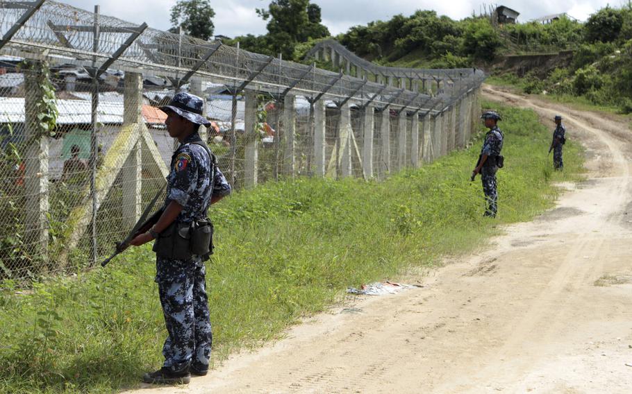 Myanmar border guards stand to provide security near a fence