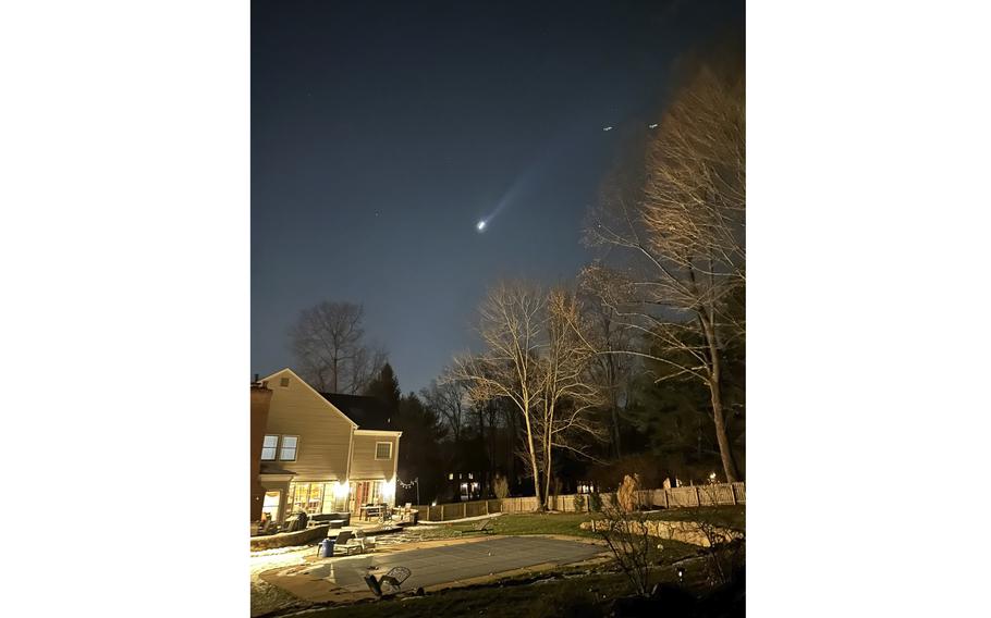 Multiple drones fly over the back yard of a suburban home at night.