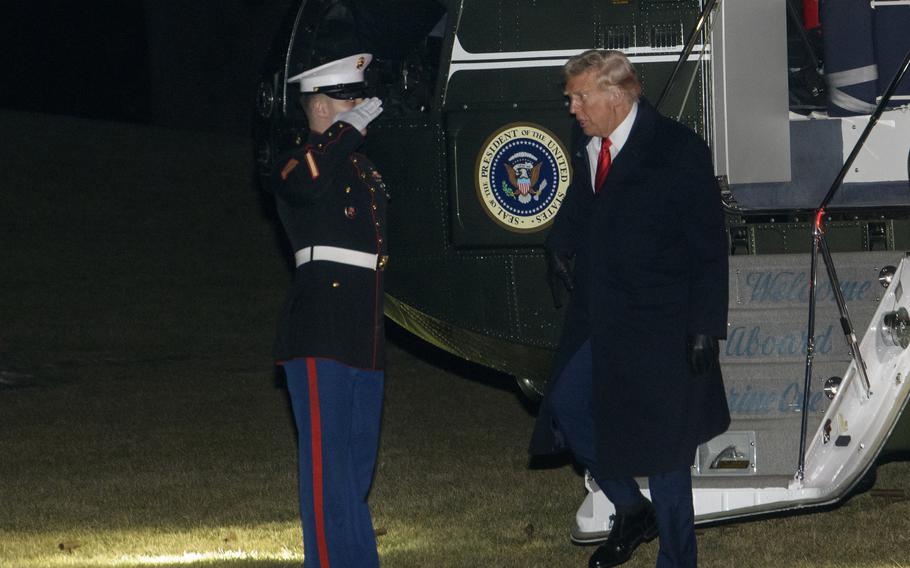 Donald Trump steps off an aircraft and greets a saluting Marine Corps honor guard member.