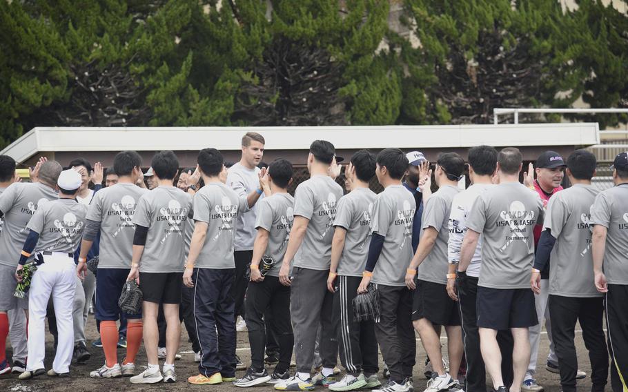 Japan Air Self-Defense Force members wearing grey t-shirts in the foreground give high fives to American service members in the background.