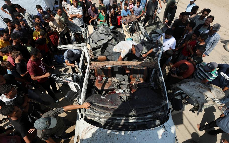 Palestinians inspect a vehicle hit in an Israeli strike, amid Israel-Hamas conflict, in Deir Al-Balah in the central Gaza Strip, June 4, 2024. 