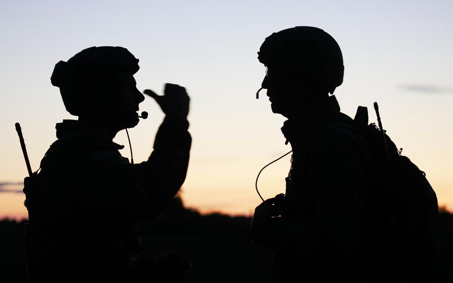 Two airmen in uniform talk while training in Estonia.