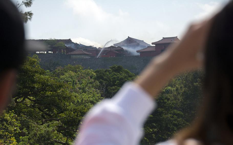 People watch from a distance as firefighters battle a blaze at Shuri Castle in Naha, Okinawa, on Oct. 31, 2019.