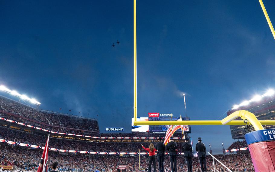 Two jets are seen above stadium bleachers against a darkening sky.