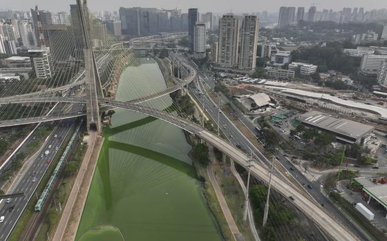 The Pinheiros River is green in Sao Paulo, Brazil, Tuesday, Sept. 10, 2024. The state's environmental authority attributes the river's new green hue to an algae bloom, the result of severe drought that has significantly lowered water levels. (AP Photo/Andre Penner)