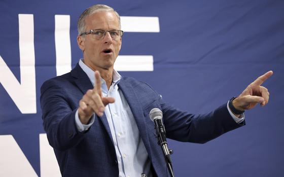 Sen. John Thune gestures with his hands while standing in front of a microphone at a campaign event.