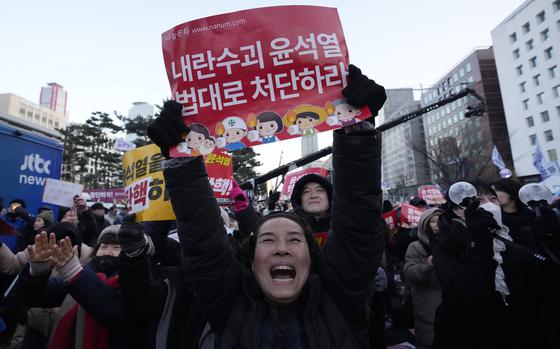 A person holds up a red sign that reads  “Punish the rebellion leader Yoon Suk Yeol” in Hangul, the official writing system of Korea.  