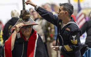 A member of the U.S. Navy sprinkles tobacco on top of a killer whale clan hat, which is considered to bring good fortune, during a Navy ceremony Saturday, Oct. 26, 2024, in Angoon, Alaska, to apologize for the 1882 military bombing of the Tlingit village in Angoon. (Nobu Koch/Sealaska Heritage Institute via AP)