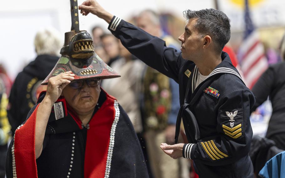 A member of the U.S. Navy sprinkles tobacco on top of a killer whale clan hat.