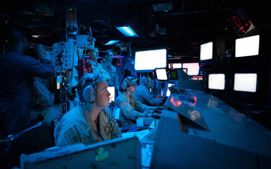 Crew members are lit by video screens aboard USS Carney.