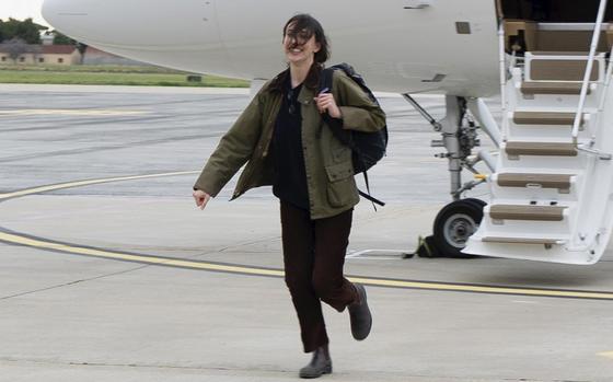 A woman half-runs a few steps away from an airplane exit ladder.