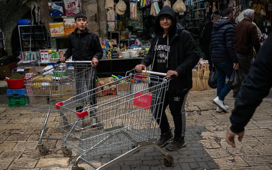 Boys with shopping carts wait for people to pay them a few shekels to carry purchased goods at the market in the Old City of Nablus.