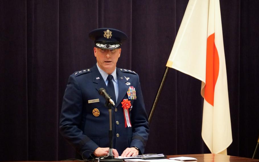 The head of U.S. Forces Japan stands next to a Japanese flag.