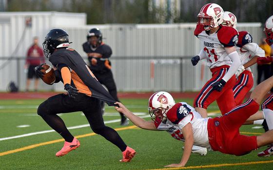 Spangdahlem receiver Logan Simmers runs away from International School of Brussels defender Haevyn McClement, who's tugging onto his jersey, during a Sept. 21, 2024, game at Spangdahlem High School in Spangdahlem, Germany.