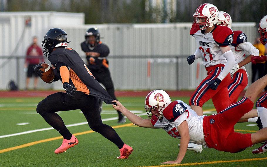 Spangdahlem receiver Logan Simmers runs away from International School of Brussels defender Haevyn McClement, who's tugging onto his jersey, during a Sept. 21, 2024, game at Spangdahlem High School in Spangdahlem, Germany.