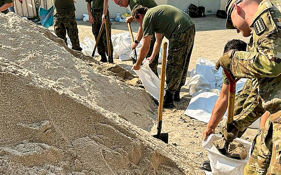 U.S. and Polish soldiers fill sandbags at Camp Karliki