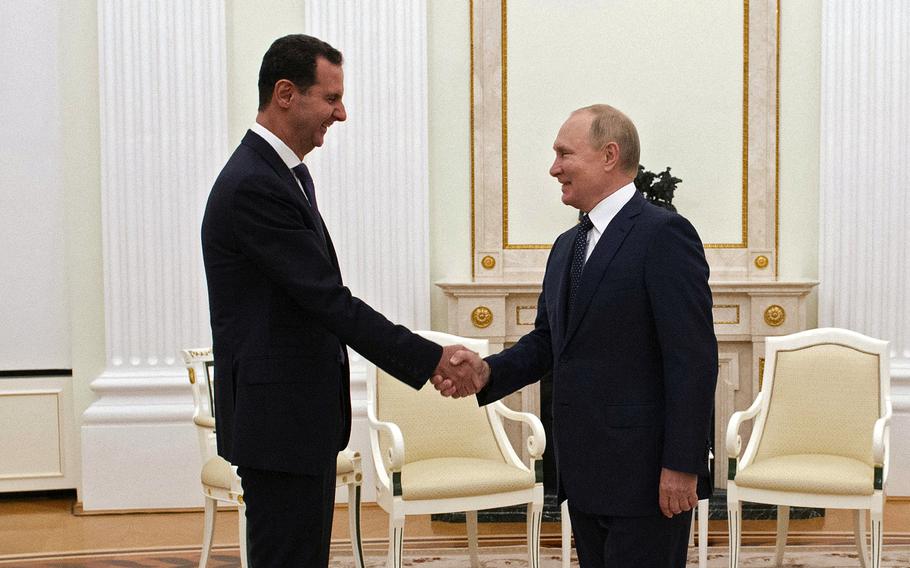 Bashar al-Assad shakes hands with Vladimir Putin.