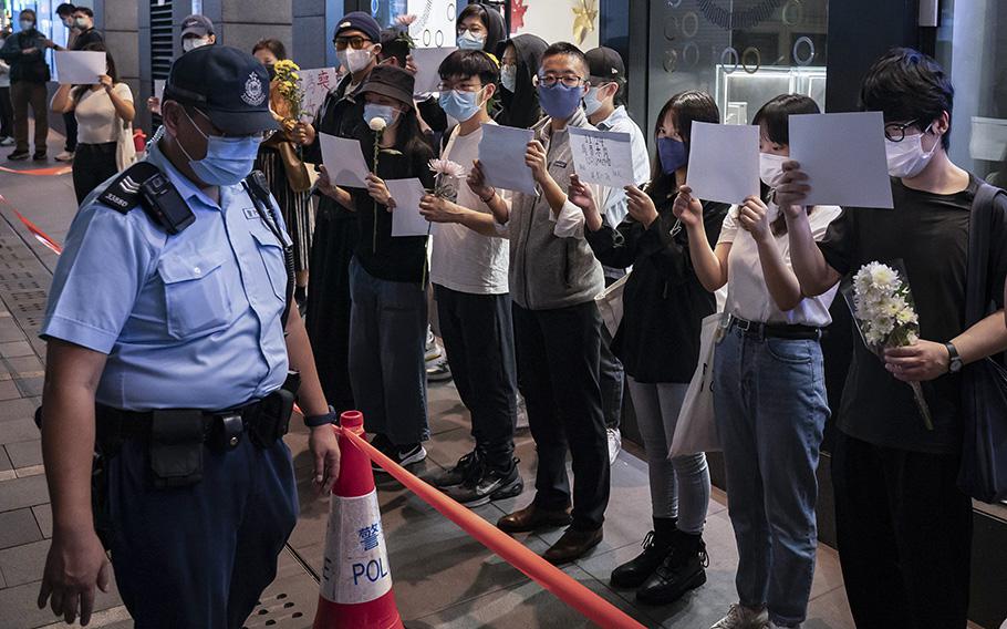 People hold sheets of blank paper and flower in protest of COVID restriction in mainland as police setup cordon during a vigil in the central district on Nov. 28, 2022, in Hong Kong. 