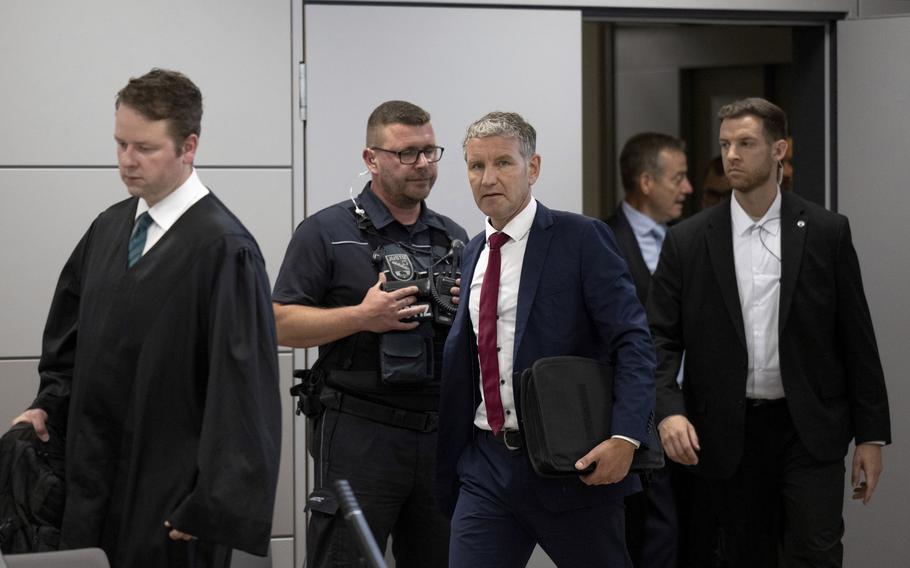 Björn Höcke, center, chairman of the Thuringian AfD, enters the courtroom of the district court shortly before the verdict is announced after his lawyer Florian Gempe, left, in Halle, Germany, Monday July 1, 2024. Höcke was convicted for the second time Monday of knowingly using a Nazi slogan at a political event. 